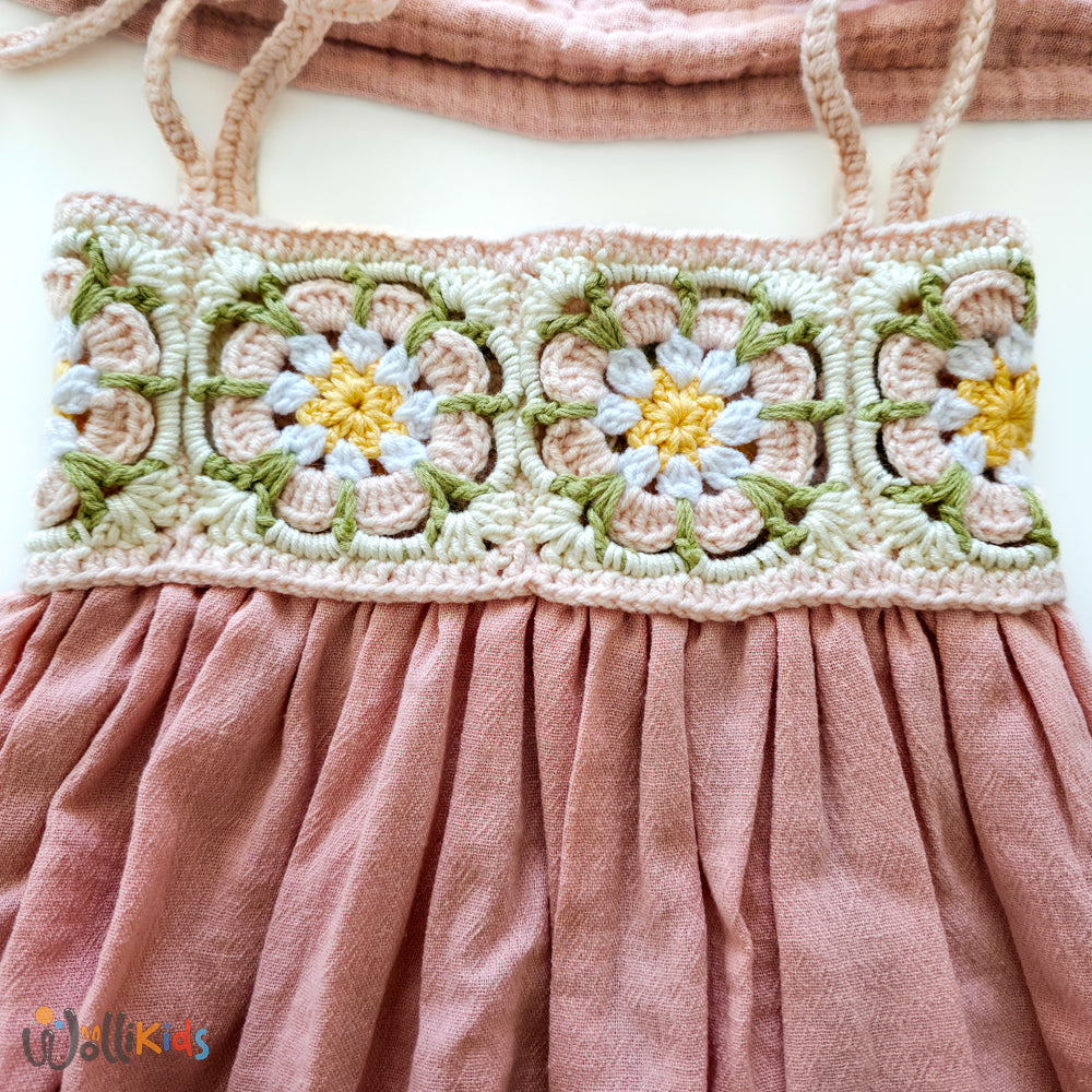 Detailansicht des gehäkelten Blumenmusters am Oberteil eines rosa Sommerkleids für Babys, mit zarten Farben und liebevoller Handarbeit.