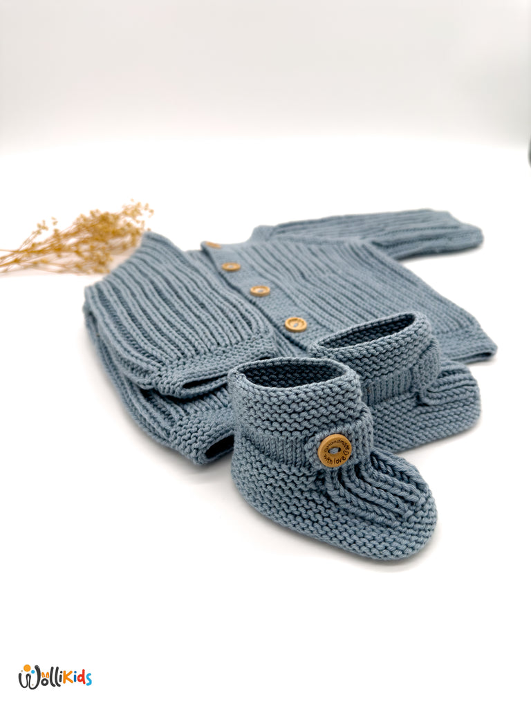 Blaues Vollpatent Babystrickjacke Set mit detaillierter Ansicht der Socken und Knöpfe, präsentiert in einem minimalistischen Stil mit Wollikids-Logo.
