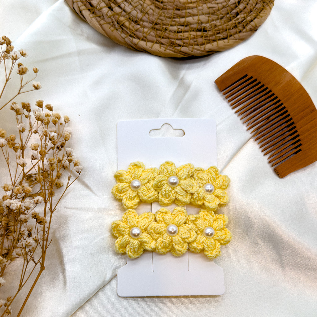 Nahaufnahme der Häkel-Haarspangen in Gelb, verziert mit Blumen und Perlenakzenten.